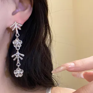 Primo piano di eleganti orecchini pendenti in argento con fiori indossati da una modella.