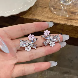 Detalle de pendientes de mariposa con piedras de cristal y detalles de flores rosas
