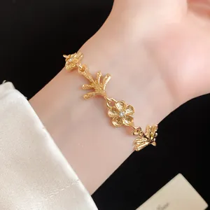 Primo piano di un bracciale placcato oro con motivi di fiori e rami irregolari organici