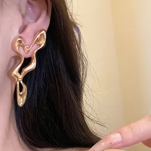 Stylish gold irregular geometric cutout metal stud earrings shown on an elegant model