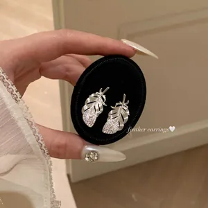 Elegant silver feather stud earrings with sparkling crystals for a minimalist chic look.