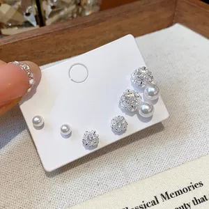 Detailed macro shot of cubic zirconia and pearl stud earring set on white card