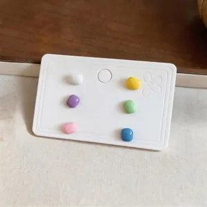 Set of six colorful square enamel stud earrings presented on a minimalist white display card