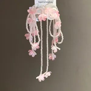 Detail shot of pink shell flower tassel earrings with white bead strands hanging on a card