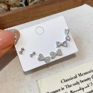 Close-up of sparkling silver bow stud earrings set with white zircons