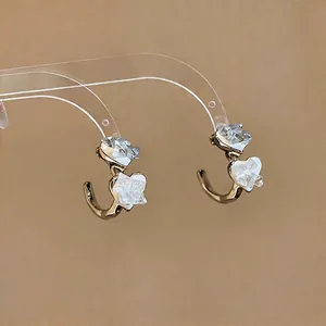 Minimalist silver needle C-shaped earrings with clear heart glass details.