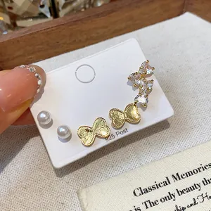 Close-up of sparkling zircon butterfly and pearl earrings with 925 silver posts