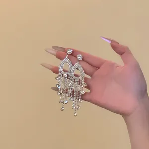 Close-up of sparkling silver needle rhinestone tassel earrings for banquet and party wear.