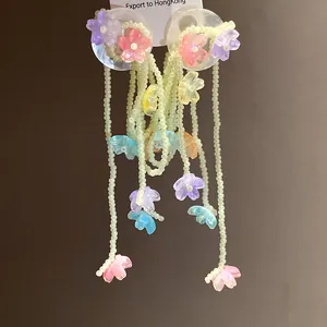 Macro view of colorful resin flowers and bead tassels on shell stud earrings
