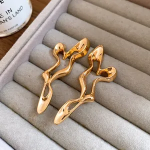 Close-up of golden geometric hollow metal earrings on a gray velvet tray