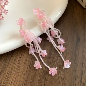 Close-up of pink beaded tassel earrings with delicate shell flower charms