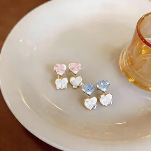 Close-up of sweet heart-shaped earrings with glass stone texture on a white plate