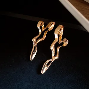 Elegant gold abstract geometric hollow earrings displayed on luxury dark velvet background