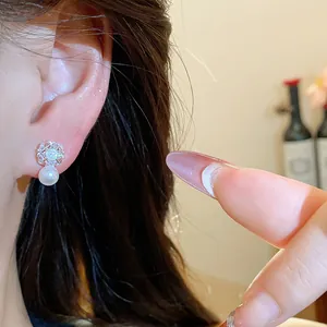 Close-up view of elegant zircon and pearl stud earring worn on a female model's ear
