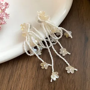 Close-up of elegant shell flower tassel earrings with delicate white seed beads