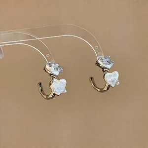 Detailed macro view of elegant C-shaped heart stud earrings with faceted glass elements