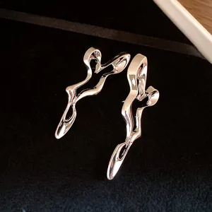 Detailed close-up of silver-tone abstract geometric hollow earrings on black velvet.