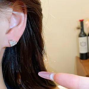 Detailed close-up of a sparkling zircon heart-shaped stud earring worn on the ear