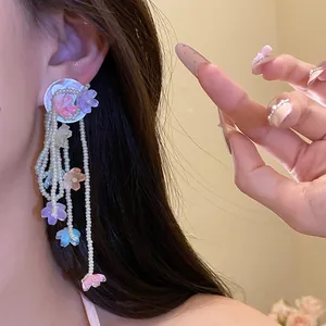 Close-up of sweet shell flower tassel earrings with delicate pearl strands on a model.