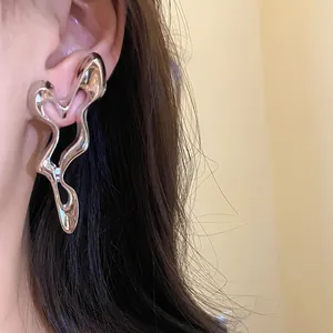 Close-up detail of silver liquid metal geometric hollow earrings worn on ear model