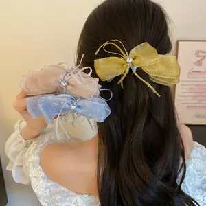 Back view of model wearing a sparkly organza bow banana hair clip in gold
