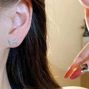 Detailed close-up of a silver bow earring encrusted with sparkling zircon studs on ear