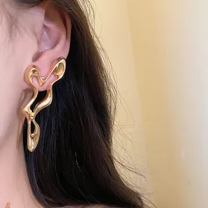 Detail view showing the metallic texture of abstract gold geometric hollow earrings on model