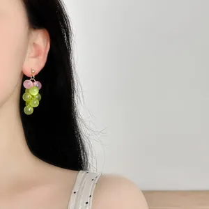 Detailed view of fresh style translucent pink and green grape bunch earrings worn on model