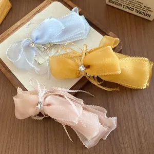 Close-up detail of three colorful organza bow banana clips with rhinestone centers