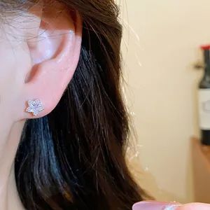 Close-up detail of a delicate star-shaped zircon stud earring on a model's ear