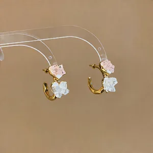 Detailed macro view of Korean C-shaped heart earrings with pink and white glass accents