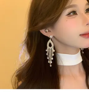 Close-up of elegant silver tassel earrings with sparkling rhinestones on a female model