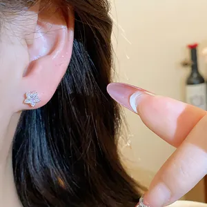 Close-up detail of a sparkling zircon star stud earring worn on the ear with silver needle