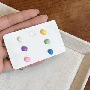 Detailed view of six pairs colorful square oil-drop stud earrings on a display card