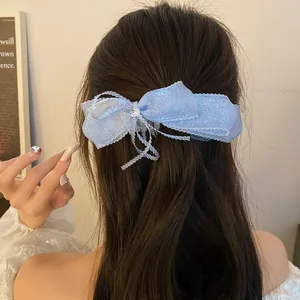 Detailed view of a light blue shimmering ribbon bow hair clip styled in a ponytail
