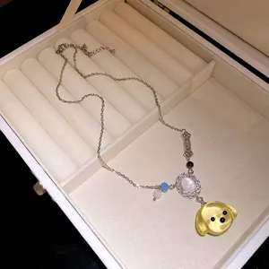 Primo piano del ciondolo a testa di cane in resina e zirconi su catena d'argento nel portagioie