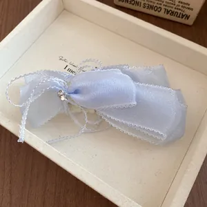 Close-up detail of a sweet light blue ribbon bow hair clip with a sparkling rhinestone