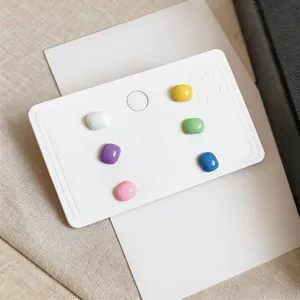 Detailed view of colorful square drip glaze stud earrings on a white display card