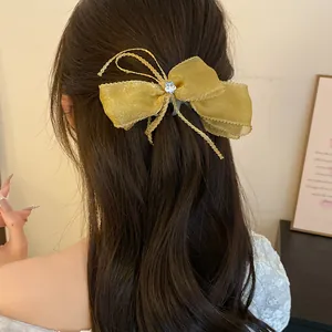 Detailed view of a sweet yellow sheer bow banana hair clip styled in a back vertical ponytail.