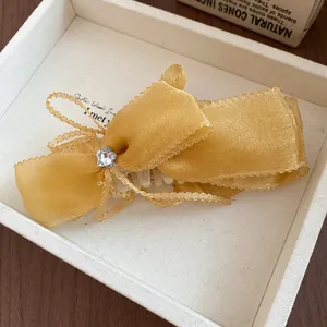 Detailed view of yellow organza bow hair clip with star-shaped crystal accent.