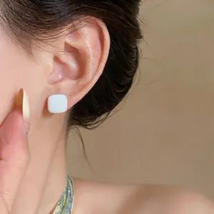 Minimalist square white enamel stud earring worn on ear detail macro photography view