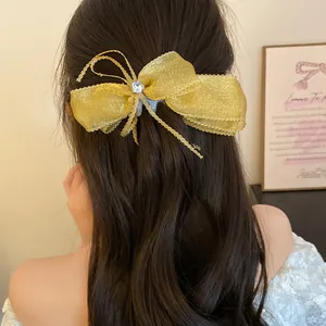 Detailed view of a sweet golden organza bow banana hair clip styled on long hair