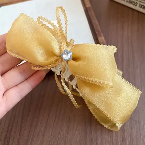 Close-up of elegant yellow chiffon bow banana hair clip with blue flower detail.