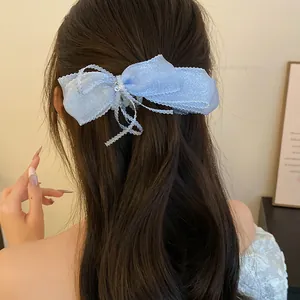 Detail of blue mesh ribbon bow banana clip styled on a wavy ponytail hair back