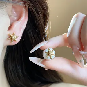 Close-up detail of luxury golden starburst flower earrings with white pearl base texture