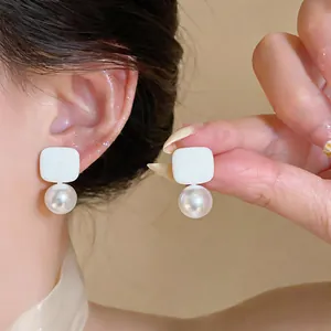 Close-up of minimalist geometric pearl drop earrings being worn by a model