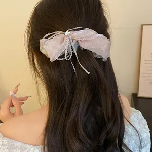 Close-up detail showing a pink glittery bow banana hair clip styled on wavy hair