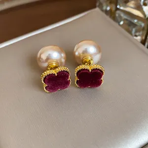 Close-up of vintage French style pearl stud earrings with burgundy velvet clover