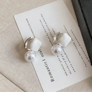 Macro detail of the elegant white geometric bead and round pearl on the silver hoop