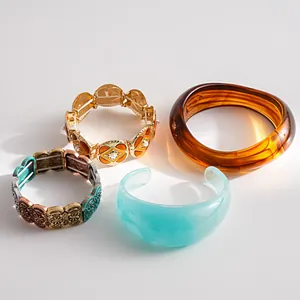 Close-up display of vintage metal stretch bracelets and translucent resin bangles set